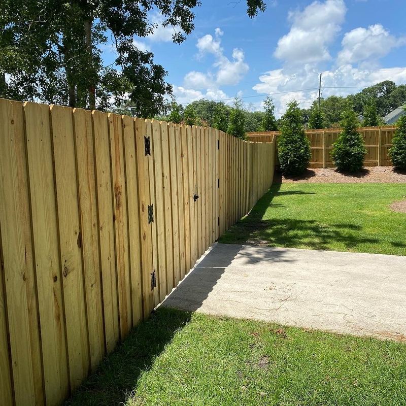 Wood privacy fence installation among oak trees