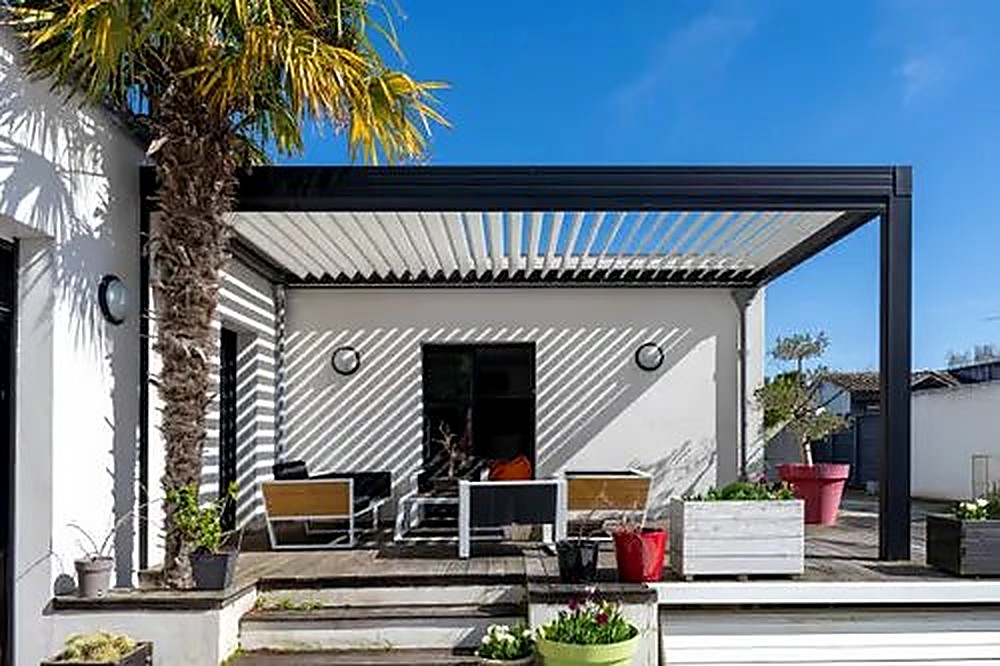 Black aluminum louvered pergola attached to a house